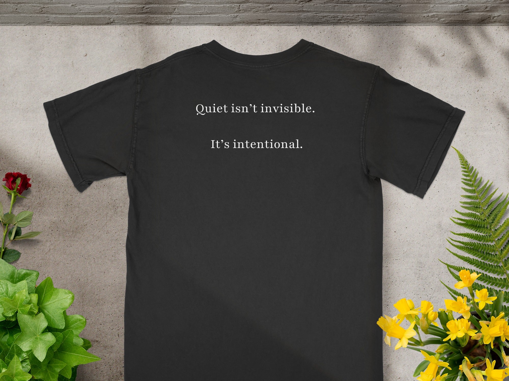 Black t-shirt with white text: "Quiet isn't invisible. It's intentional."