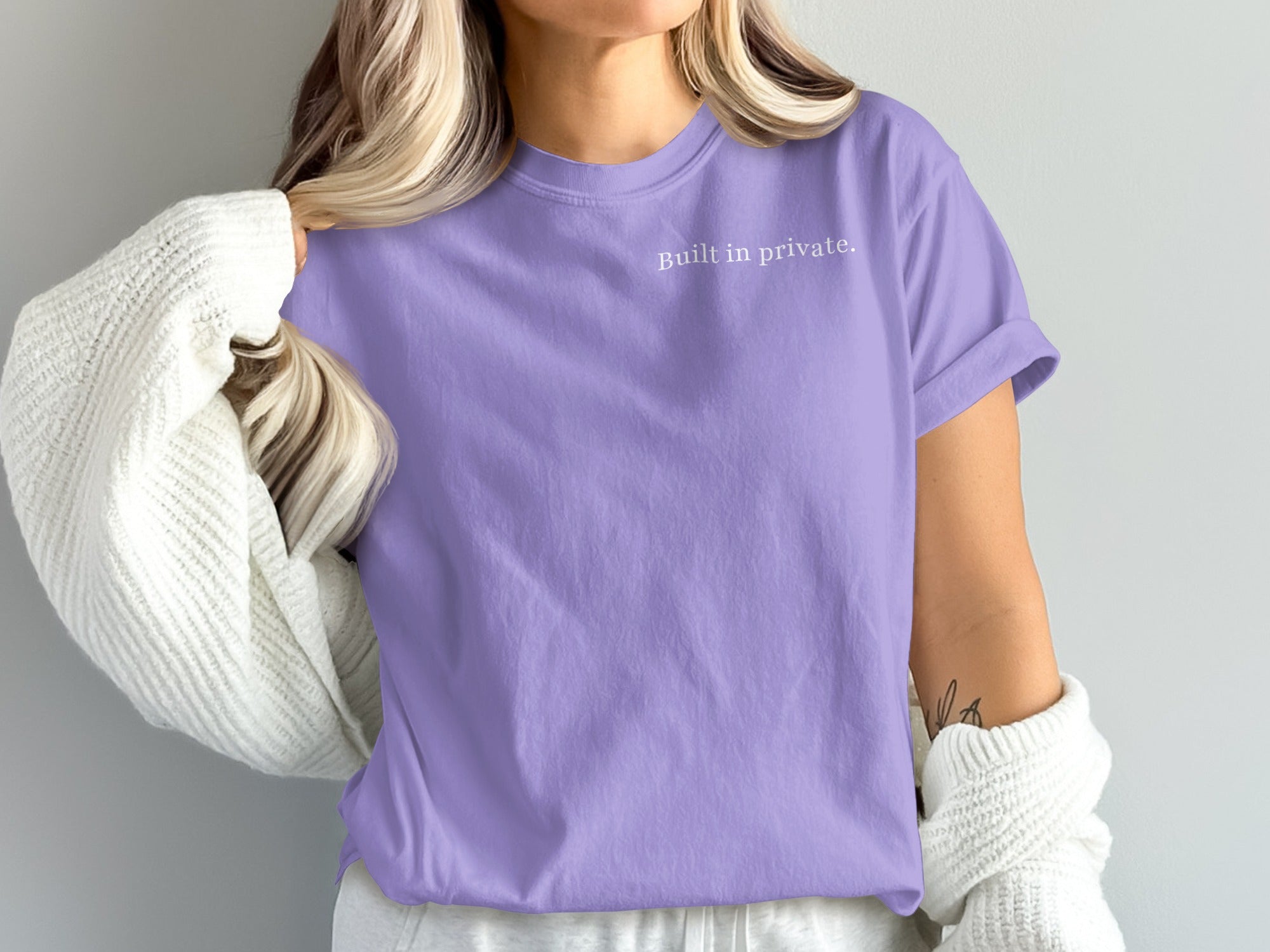 Purple t-shirt with "Built in private." text, worn by a person with blonde hair.