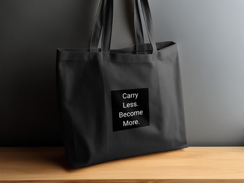 Black tote bag with white text: "Carry Less. Become More."