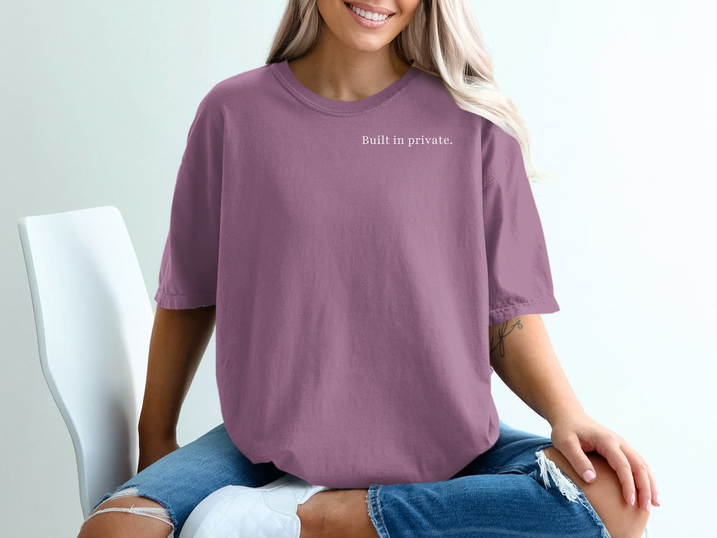 Woman wearing a plum colored t-shirt with "Built in private." text.