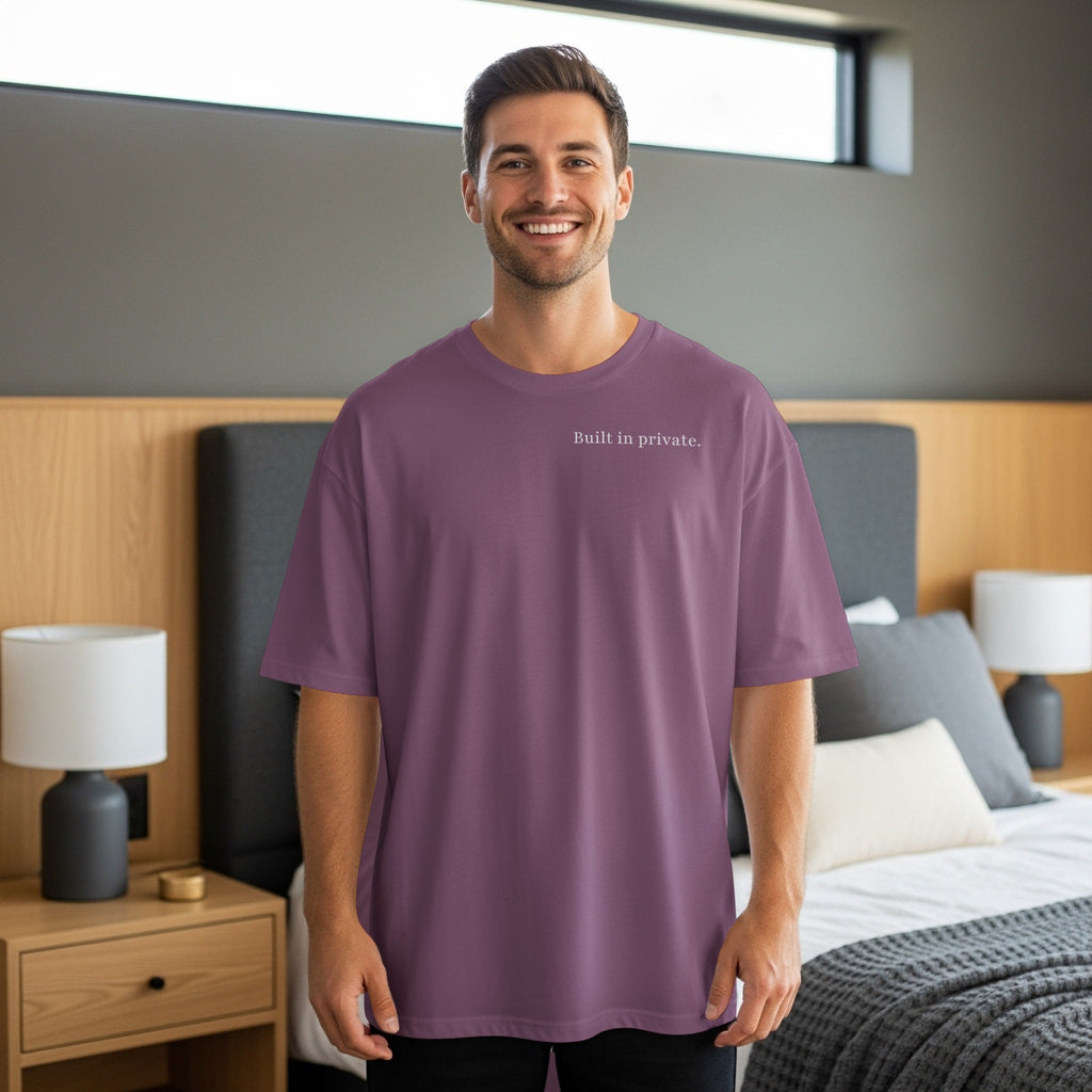 Man wearing a purple oversized t-shirt with "Built in private." text across chest.